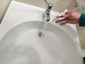 Pestrid stručnjak provodi mjerenje temperature vode digitalnim termometrom kao dio politike kvalitete i kontrole Legionelle.